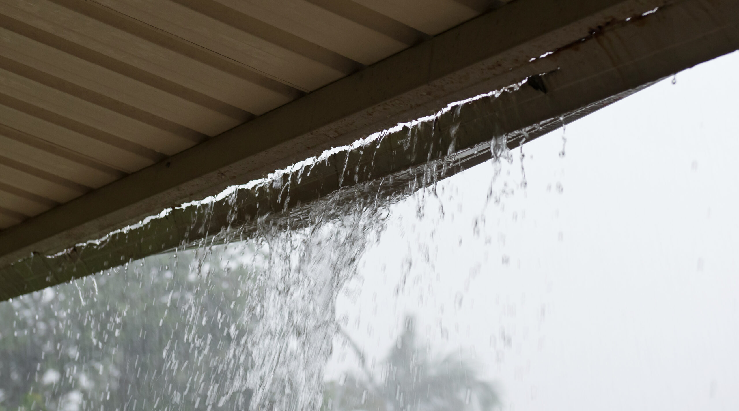 Overflowing gutter during heavy rainstorm — clogged gutters cause water damage to Nashville homes