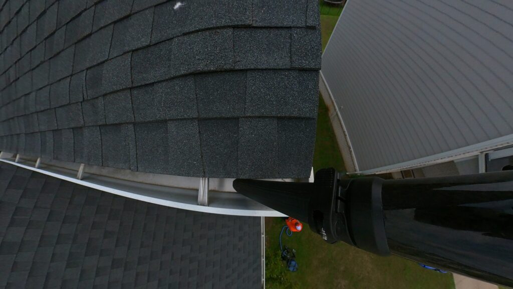 View from roof showing ground-level gutter vacuum pole reaching into two-story gutters without ladders in Nashville