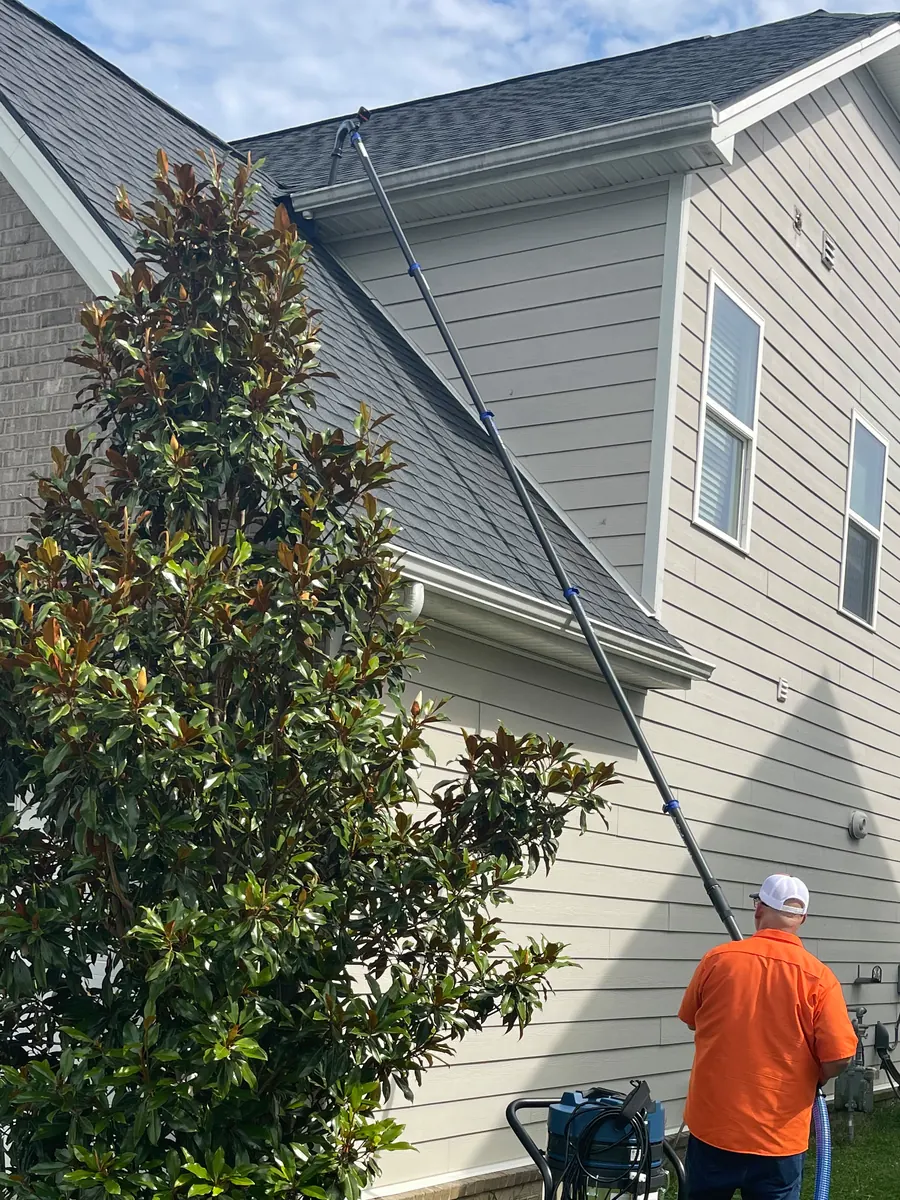 Ground Force Gutters technician cleaning two-story gutters from the ground with industrial vacuum pole in Nashville Tennessee