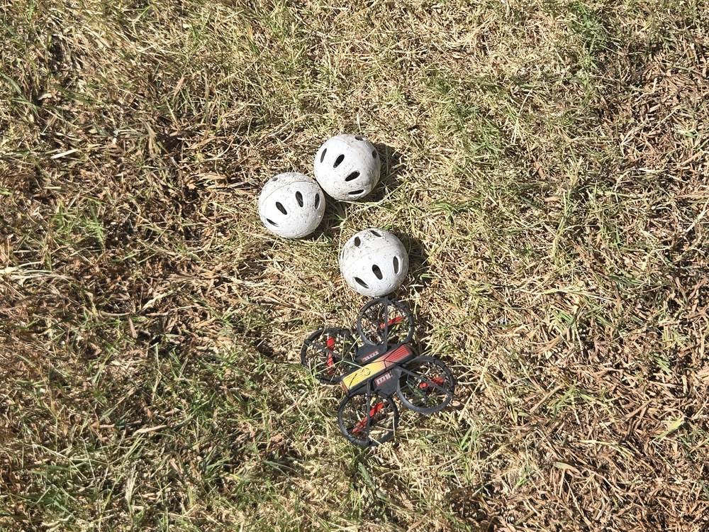 Three wiffle balls and a toy drone on a lawn after being vacuumed out of a two-story gutter in Mt. Juliet, TN